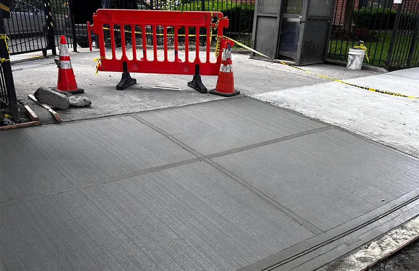 New concrete sidewalk poured at an apartment building entrance, taped off to cure, sidewalk repair by Sidewalk Repair Near Me in NYC