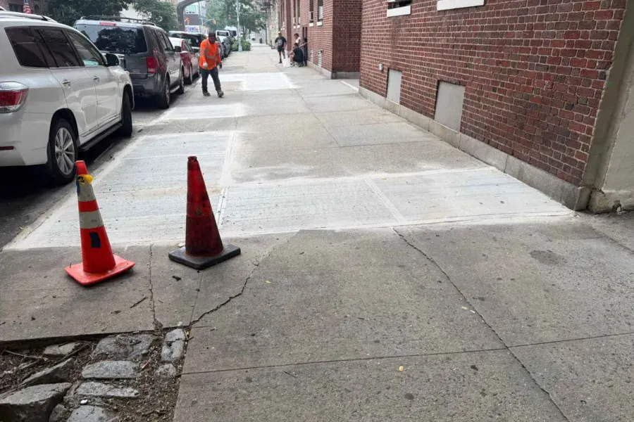 After: New concrete sidewalk beside a brick rental building in Sunnyside, Queens