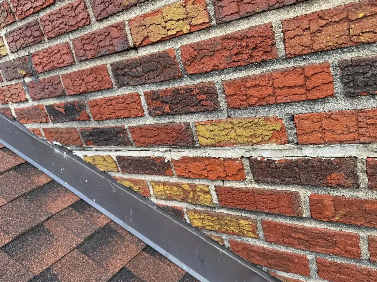Repointed mortar joints on a brick wall above a roof edge, brick pointing by Sidewalk Repair Near Me in NYC