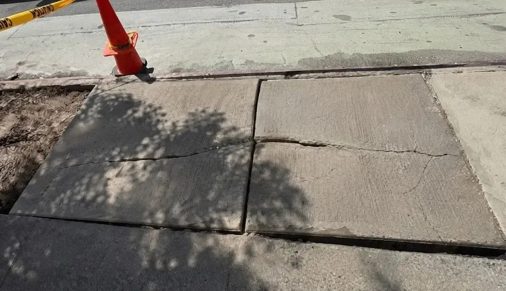 Cracked and lifted sidewalk flags in the East Village before replacement, concrete work by Sidewalk Repair Near Me in NYC