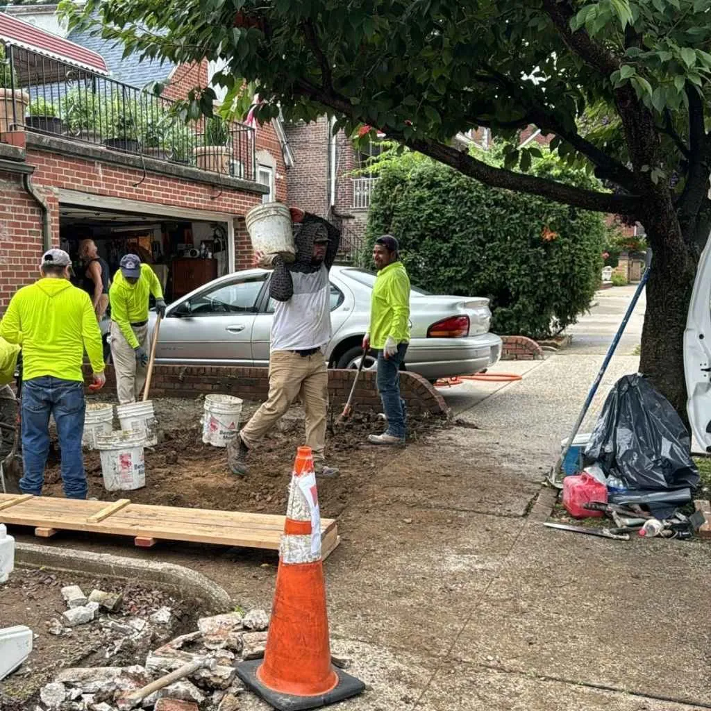 Crew carrying out broken concrete during a sidewalk and driveway replacement, concrete work by Sidewalk Repair Near Me in NYC