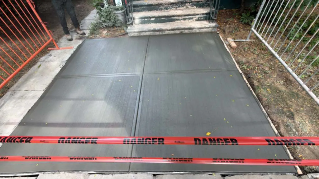 New concrete walkway taped off to cure, concrete work by Sidewalk Repair Near Me in NYC