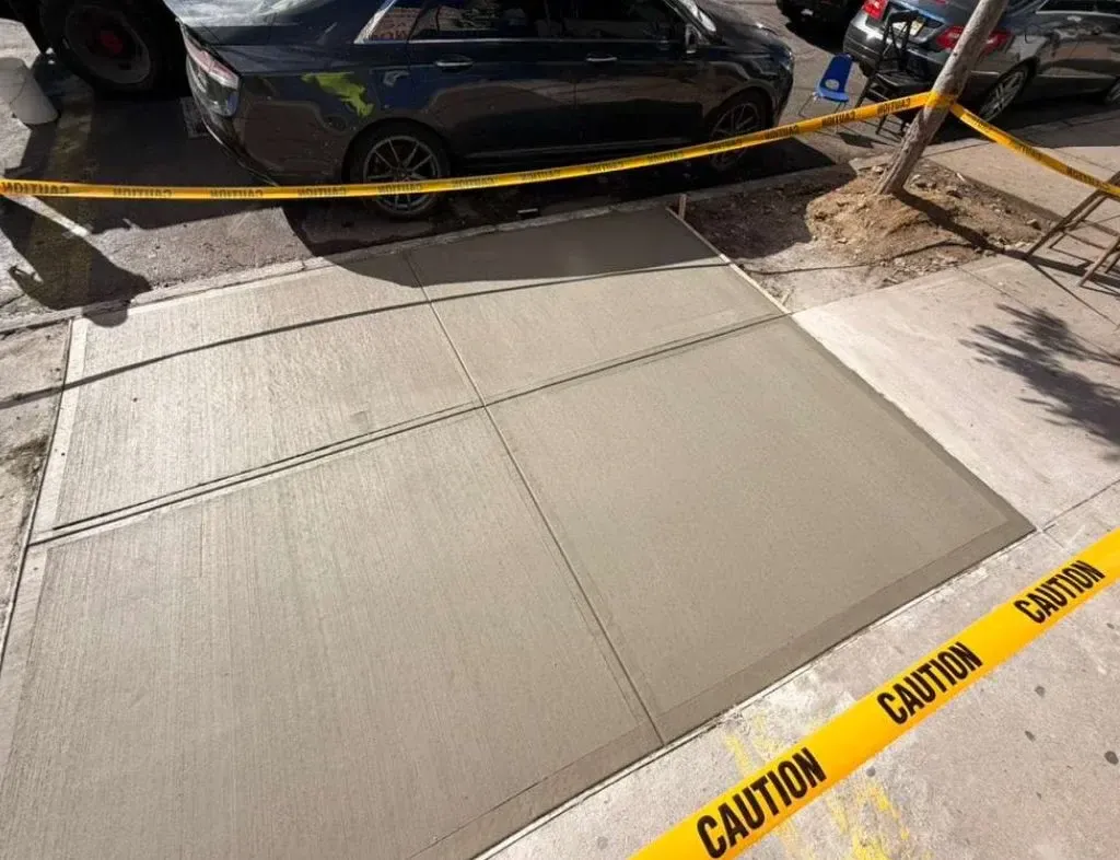 Replaced sidewalk slabs with caution tape across the work area, concrete work by Sidewalk Repair Near Me in NYC