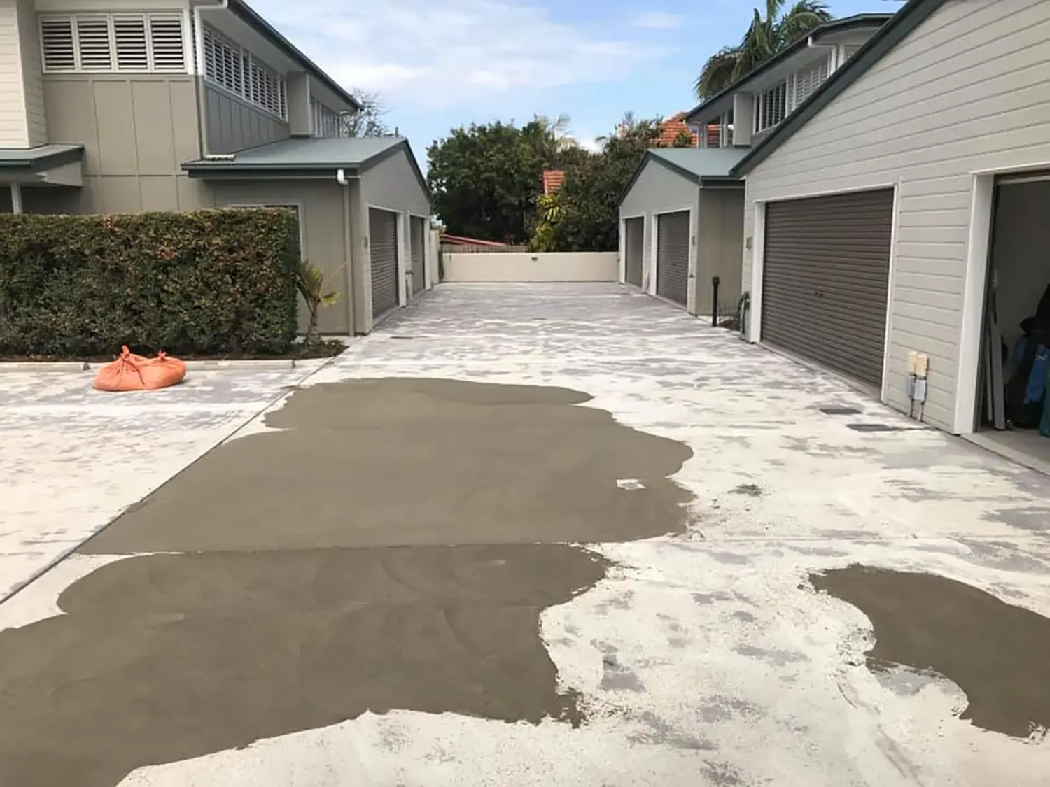 Freshly poured concrete on a shared driveway between rows of garages, concrete driveway work by Sidewalk Repair Near Me in NYC