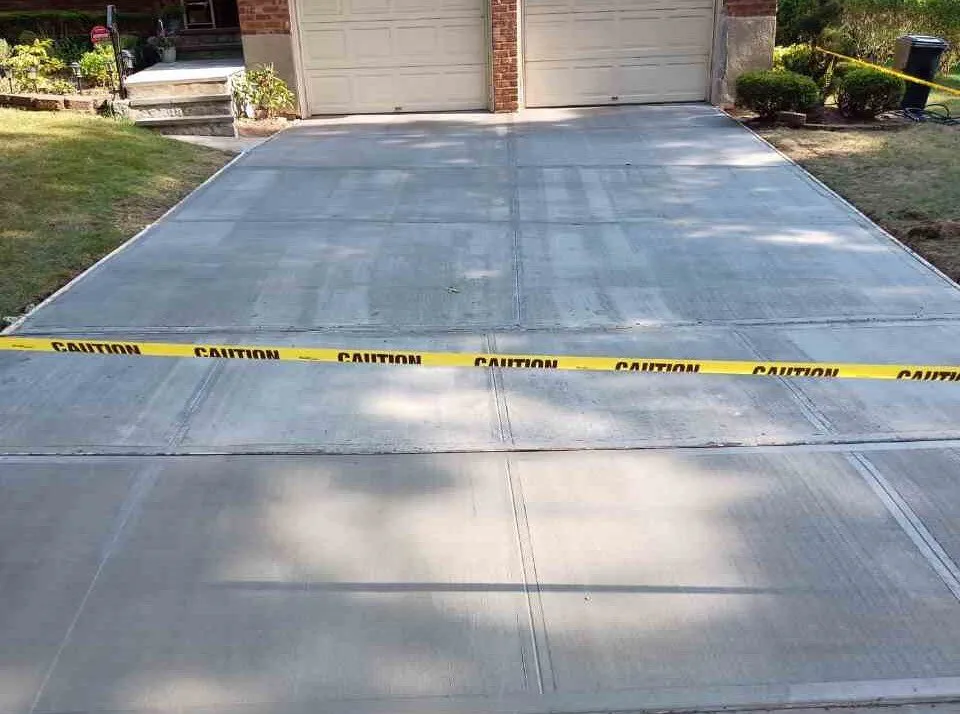 New concrete driveway leading to a two car garage, taped off to cure, concrete driveway work by Sidewalk Repair Near Me in NYC
