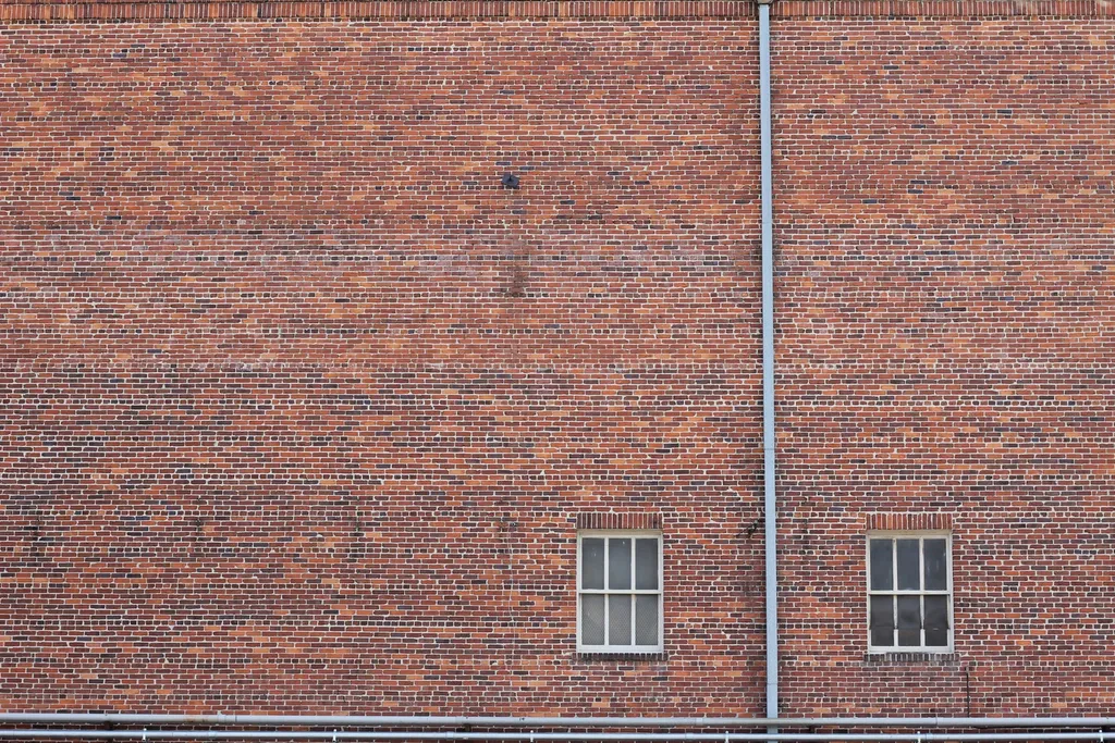 Large brick building wall with two small windows