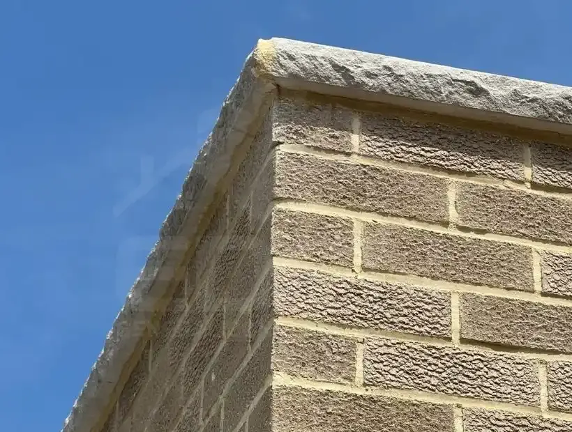 Parapet wall with a stone coping against a blue sky, masonry work by Sidewalk Repair Near Me in NYC