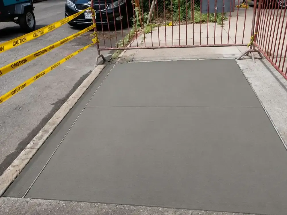 Freshly poured sidewalk flag protected by caution tape and metal barriers, sidewalk repair by Sidewalk Repair Near Me in NYC