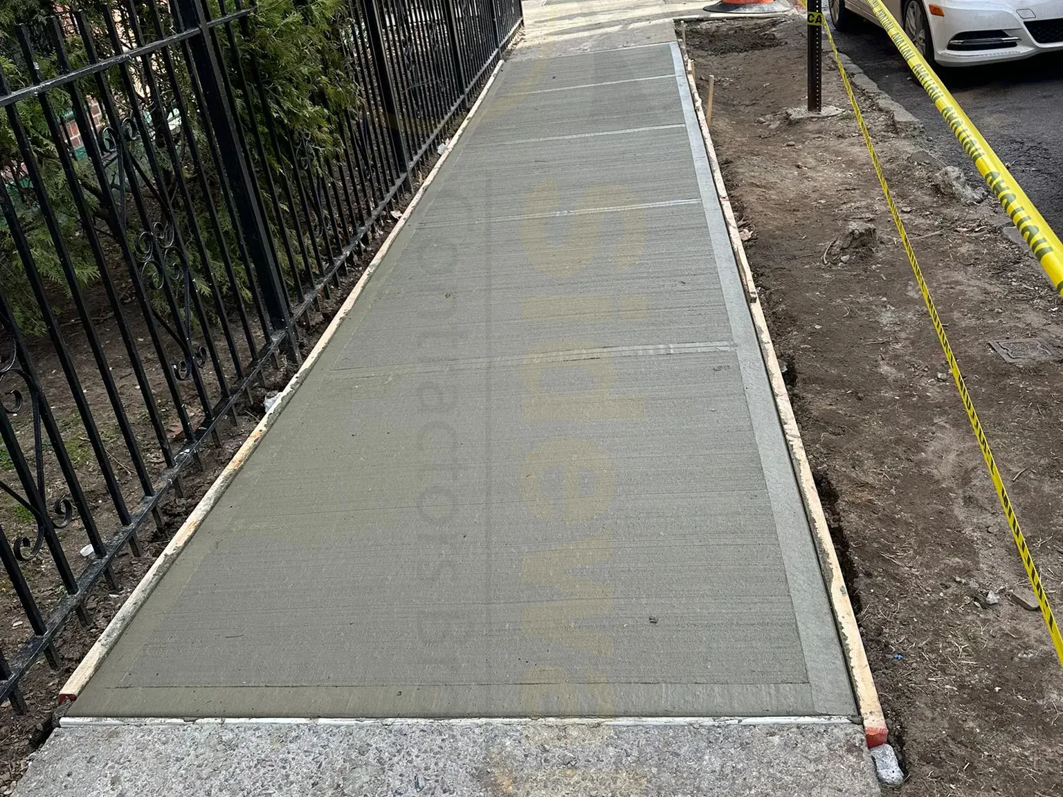 Fresh concrete sidewalk formed beside an iron fence, sidewalk repair by Sidewalk Repair Near Me in NYC