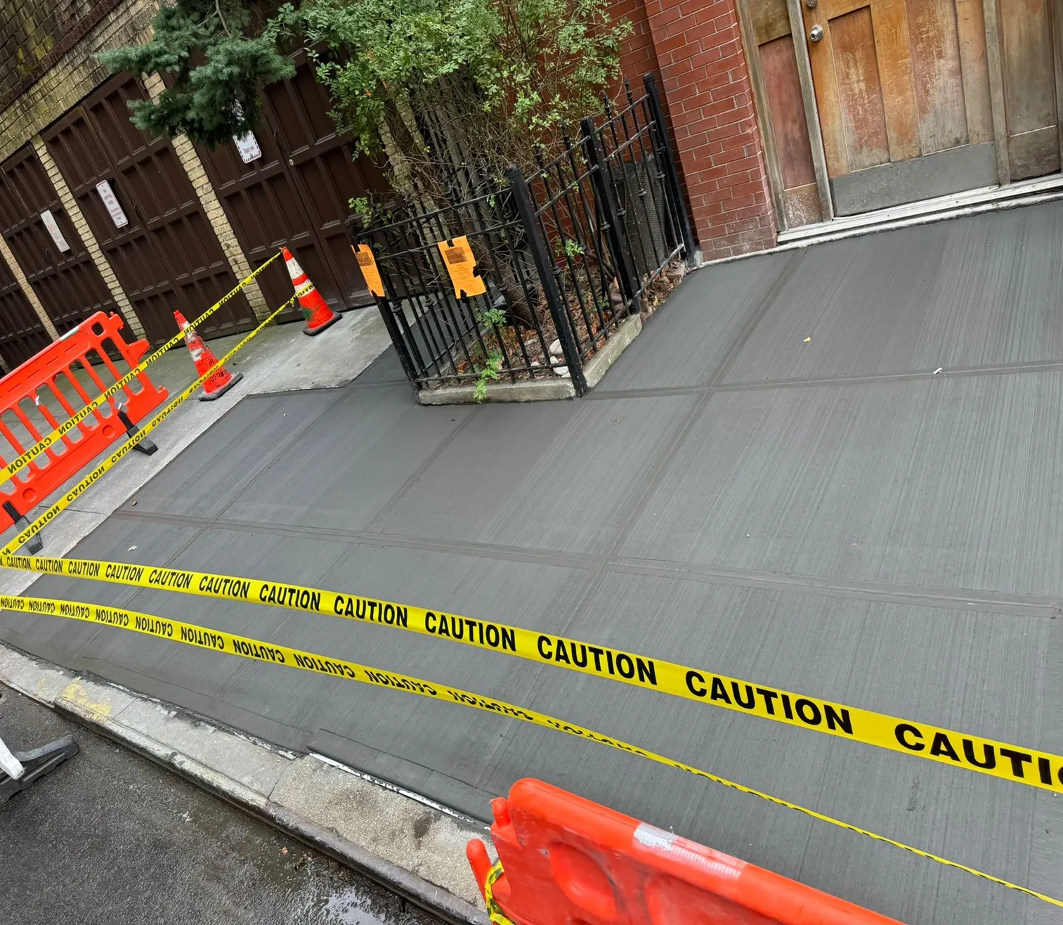 Fresh concrete sidewalk at a gated entrance, closed with caution tape, sidewalk repair by Sidewalk Repair Near Me in NYC