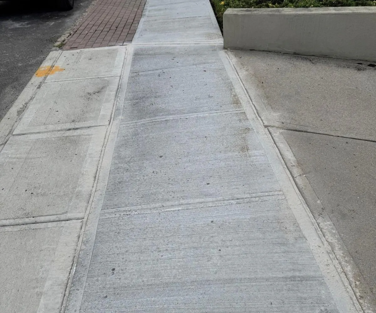 New concrete sidewalk with a brick paver strip at the curb, sidewalk repair by Sidewalk Repair Near Me in NYC