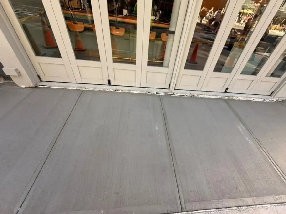 New concrete sidewalk slabs in front of a storefront in Manhattan, sidewalk repair by Sidewalk Repair Near Me in NYC