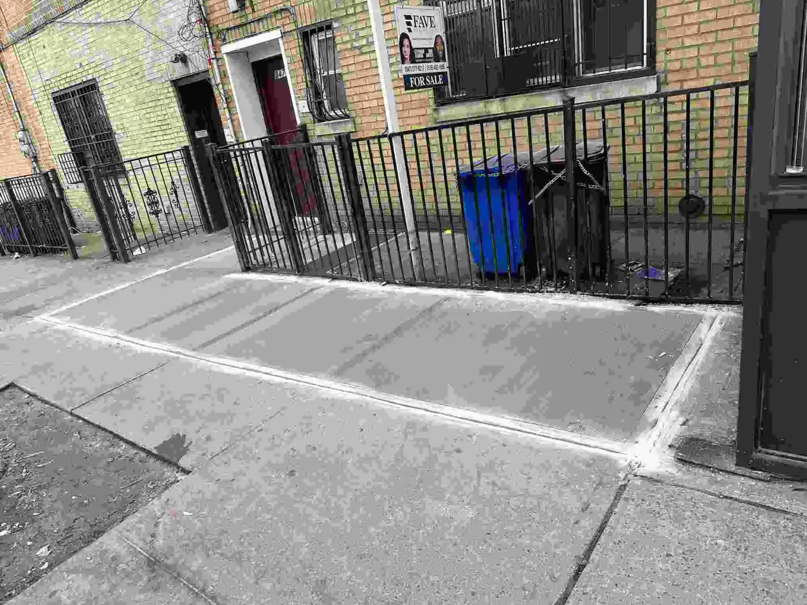 Replaced sidewalk flags in front of an iron fence and brick row houses, sidewalk repair by Sidewalk Repair Near Me in NYC