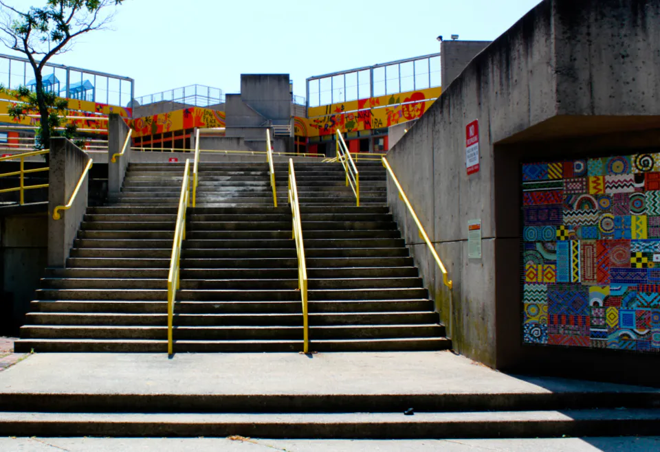 Concrete stairs with yellow handrails between concrete walls