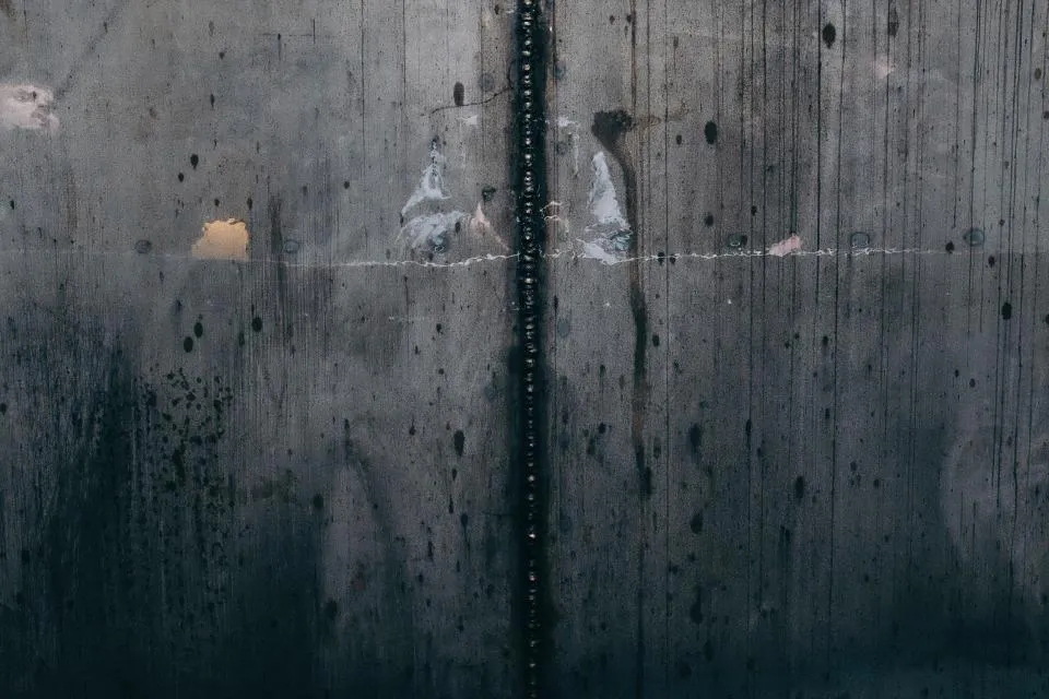 Concrete wall with dark water stains running down from a joint